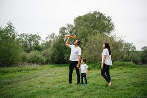 content famille mère père et enfant fils sur la nature sur le coucher du soleil. maman, papa et enfant en riant et étreindre, profiter la nature dehors. ensoleillé jour, bien ambiance. concept de une content famille. photo