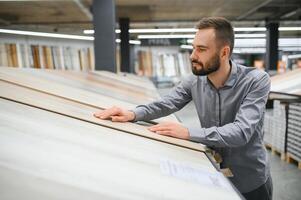 une Jeune homme choisit stratifié sol dans le Matériel boutique photo