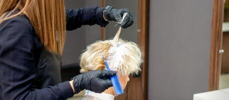 coloration femelle cheveux dans le cheveux salon. Jeune femme ayant sa cheveux teint par esthéticien à le beauté parloir. photo