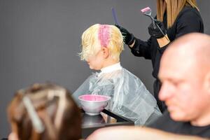 coloration femelle cheveux dans le cheveux salon. Jeune femme ayant sa cheveux teint par esthéticien à le beauté parloir. photo