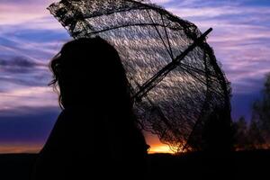 femme avec une dentelle parapluie dans le le coucher du soleil photo