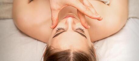 visage massage avec les doigts de une masseur. femelle faciale peau se soucier à une beauté spa salon. photo