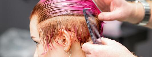 coiffant femelle cheveux. Masculin coiffeur fait du coiffure pour une Jeune femme dans une beauté salon. photo