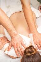 retour massage avec quatre mains dans le spa salon. deux massage thérapeutes faire une retour massage pour une Jeune femme. photo