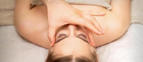 visage massage avec les doigts de une masseur. femelle faciale peau se soucier à une beauté spa salon. photo