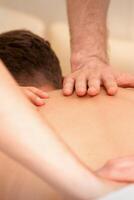 Jeune homme recevoir retour massage dans quatre mains dans spa beauté salon. photo