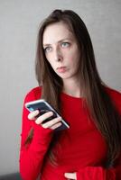 magnifique Jeune femme avec bleu yeux et longue cheveux dans une magnifique veste montres le nouvelles sur le téléphone photo