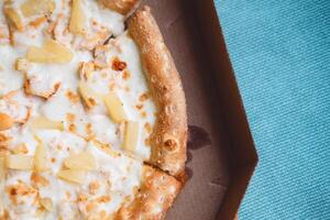 délicieux italien Pizza avec Ananas et poulet Viande dans une boîte sur une bleu Contexte photo
