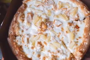 délicieux italien Pizza avec Ananas et poulet Viande dans une boîte sur une bleu Contexte photo