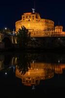 nuit vue de le castel saint ange forteresse et le saint ange pont réfléchi dans le Tibre rivière photo