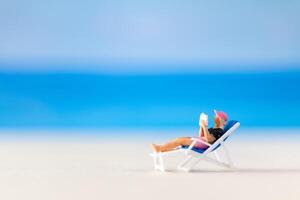 miniature gens , une femme relaxant sur une plate-forme chaise et en train de lire une livre photo