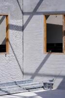 la perspective vue de en bois fenêtre cadres sur béton mur avec beaucoup carbone acier rectangulaire tubes et travail outils à l'intérieur de maison construction site dans verticale Cadre photo
