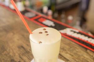 une du froid café cocktail dans une clair verre avec une paille sur une en bois bar compteur photo