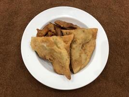 solated Haut vue de qeema samosa et bassin pakora dans blanc plaque, populaire Indien ou pakistanais rue nourriture casse-croûte sur blanc arrière-plan, diwali dîner ou iftar repas. photo