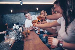 concept de loisirs et de communication. groupe d'amis souriants heureux appréciant des boissons et parlant au bar ou au pub photo