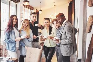 les jeunes gens d'affaires qui réussissent parlent et sourient pendant la pause-café au bureau photo