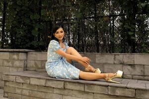 tangerang, Indonésie - décembre 9 2023 une femelle modèle séance sur une pierre chaise portant une bleu robe et or chaussures. montrant une sexy pose photo