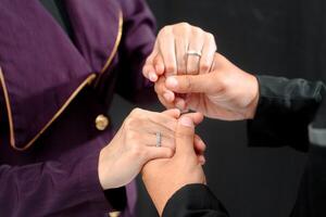 mariage bague photo tirer concept une homme portant une formel noir costume et violet attacher et femme avec violet costume est en portant une mariage bague