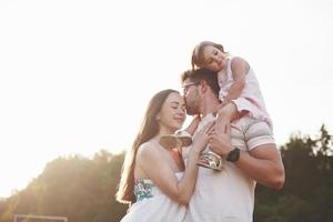 famille heureuse, père de mère et fille de bébé dans la nature au coucher du soleil photo