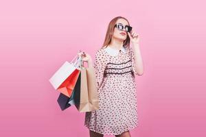 portrait de jeune femme souriante heureuse avec des sacs à provisions sur fond rose photo