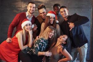 la nouvelle année arrive. groupe de jeunes multiethniques joyeux dans des chapeaux de père Noël à la fête, posant un concept de style de vie émotionnel photo