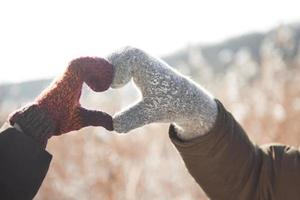 les mains des femmes et des hommes dans un gant plié en forme de coeur. notion d'hiver. chute de neige. photo