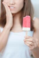 les dents sensible à du froid concept. femme tenir la glace crème et ayant mal aux dents et douleur après manger. dent pourriture ou gencive maladie, broyage les dents et stress, exposé nerf racines, fissure et fuyant les gencives photo