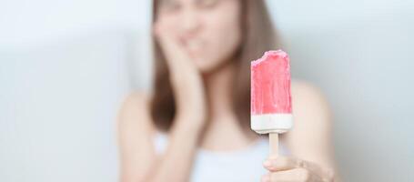 les dents sensible à du froid concept. femme tenir la glace crème et ayant mal aux dents et douleur après manger. dent pourriture ou gencive maladie, broyage les dents et stress, exposé nerf racines, fissure et fuyant les gencives photo