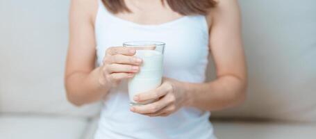 Lait boisson et du quotidien routine concept. Jeune femme en buvant Lait avec haute calcium et nutrition à maison, femme en portant soja Lait sur verre avec protéine. en bonne santé, bien-être et content mode de vie photo