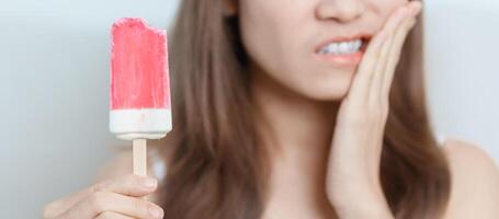 les dents sensible à du froid concept. femme tenir la glace crème et ayant mal aux dents et douleur après manger. dent pourriture ou gencive maladie, broyage les dents et stress, exposé nerf racines, fissure et fuyant les gencives photo