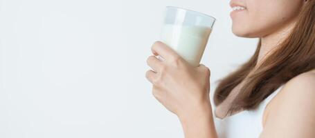 Lait boisson et du quotidien routine concept. Jeune femme en buvant Lait avec haute calcium et nutrition à maison, femme en portant soja Lait sur verre avec protéine. en bonne santé, bien-être et content mode de vie photo