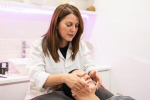 esthéticien Faire beauté massage sur visage de client dans spa photo