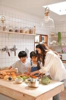 des moments heureux en famille lorsque les enfants aident maman à cuisiner dans la cuisine. photo