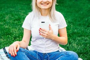 femme dans les écouteurs et smartphone sur l'herbe verte photo