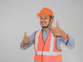 une homme portant construction casque souriant et donner deux les pouces en haut photo