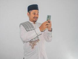 musulman asiatique homme souriant content lorsque envoyer des SMS en utilisant le sien mobile téléphone photo