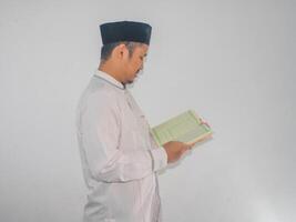 musulman asiatique homme souriant à le Al qur'an et tandis que en portant une Al Quran photo