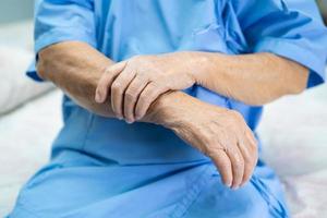 Une patiente asiatique âgée ou âgée ressent une douleur au bras et à la main sur le lit dans la salle d'hôpital de soins infirmiers, concept médical solide et sain. photo