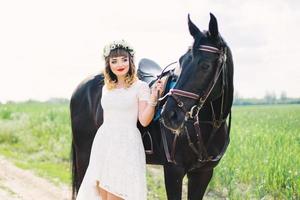 fille aux lèvres rouges près d'un cheval noir photo