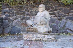 Tcherkassy, Ukraine - octobre 20, 2021 joyeux Buddah béton gris statue proche à blanc lotus bouddhiste temple photo