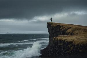 une homme des stands sur le bord de une falaise surplombant le océan photo