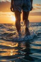 une la personne en marchant dans le océan à le coucher du soleil photo