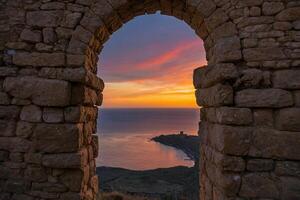 le coucher du soleil par un arcade dans un vieux pierre bâtiment photo