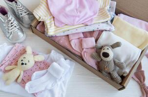 bébé et enfant vêtements et tricoté jouets dans carton boîte. photo