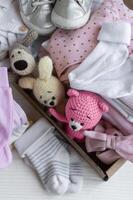 bébé vêtements, tricoté jouets, chaussettes et des chaussures dans boîte. photo