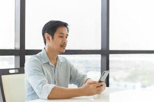 portrait d'un bel homme relaxant à l'aide d'un téléphone intelligent à la maison. photo