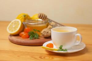 gingembre thé avec menthe et citron. en bonne santé et chaud boire. liquide mon chéri dans pot de miel. blanc tasse sur en bois Contexte. sélectif se concentrer. photo