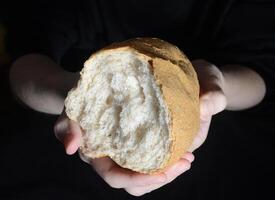 femelle mains en portant une divisé pain de pain. concept de cuisson. fermer. photo