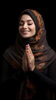 arabe femme portant écharpe est prier et souriant sur noir Contexte photo