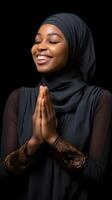 africain femme portant écharpe est prier et souriant sur noir Contexte photo